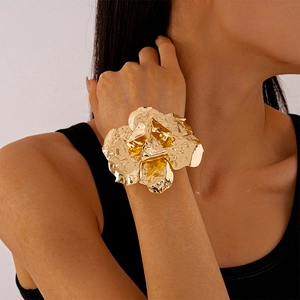 Macro detail of golden irregular pleated flower cuff bracelet on model's wrist