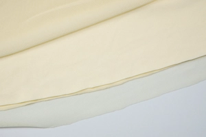 Detailed macro view of cream knitted fabric layered over breathable white mesh material