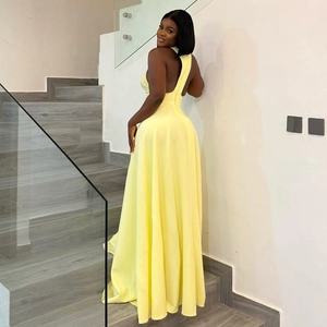 Detail of light yellow halter neck backless maxi dress with flowy pleated hemline