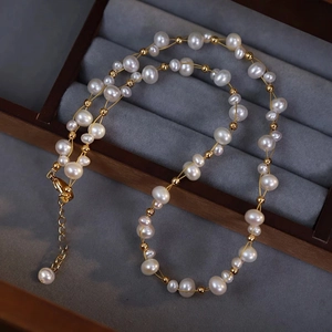 Double-layer woven pearl necklace with gold beads on a premium grey velvet jewelry display