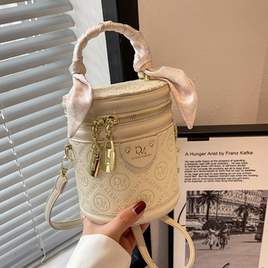 Elegant white cylindrical bucket bag with embossed leather and silk scarf handle detail