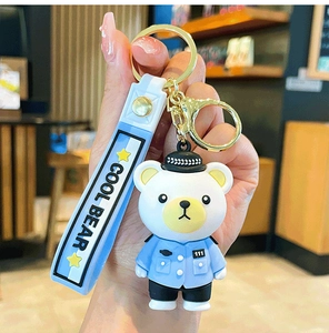 Detail of cute police bear keychain with blue silicone wrist strap and gold metal clasp