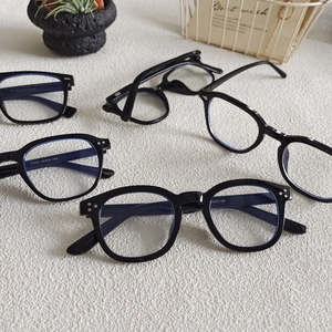 Occhiali neri quadrati con lenti anti-luce blu su un tappeto dalla consistenza morbida