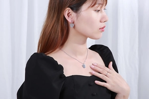 Close-up of a silver multi-layered heart necklace and earring set on a model