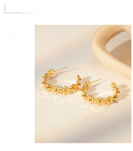 Detail view of gold flower-shaped C-style hoop earrings with daisy floral pattern