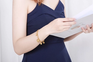 Gros plan d'un bracelet doré avec des cœurs sur un mannequin en robe bleu foncé