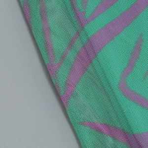 Detailed view of mint green and purple mesh fabric with wave pattern texture