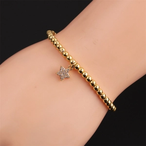 Détail du bracelet en perles dorées avec pendentif étoile serti de zircons pour femme