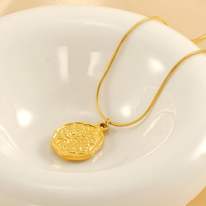 Macro detail of gold coin pendant with hammered texture and sleek snake chain