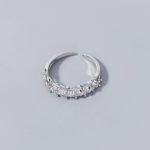 Detail of silver safety pin ring featuring shimmering zircon stones and wavy band design
