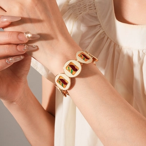 Macro shot of vintage gold enamel bracelet with colorful abstract patterns on female wrist
