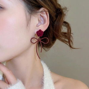 Elegant red velvet rose and bow earrings with long streamers on female model