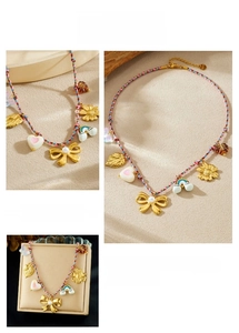 Close-up of colorful braided necklace featuring a golden bow with pearl and rainbow charms