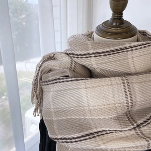 Classic beige and brown plaid scarf with tassels on a mannequin for autumn winter