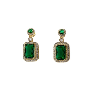 Boucles d'oreilles élégantes en cristal vert taille émeraude plaquées or sur fond blanc