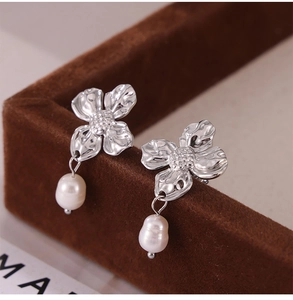 Macro shot of silver petal earrings with white freshwater pearl on dark velvet