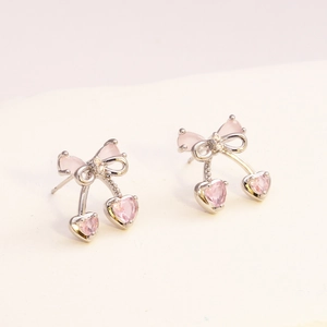 Dettaglio di orecchini a ciliegia con zircone a cuore rosa e fiocchi in metallo argento