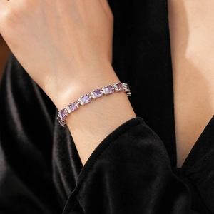 Detalle de pulsera plateada con circonitas moradas en muñeca sobre fondo negro lujoso