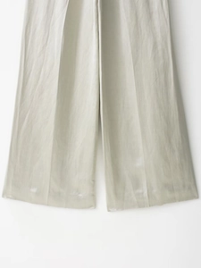 Dettaglio di pantaloni larghi grigio chiaro con trama in raso di seta e finitura lucida