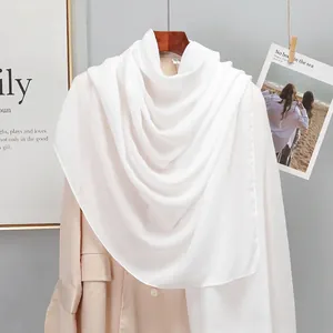 Close-up of white linen shawl on a wooden hanger with clean edge stitching details
