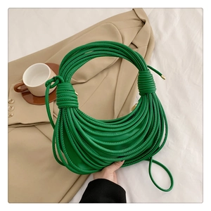 Detail of green knotted shell bag with unique rope handle on a beige blazer background