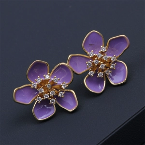 Macro detail of purple enamel flower stud earrings with gold trim and inlaid zircons