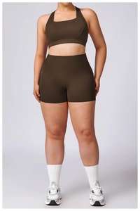 Detail of high-waisted dark brown sports bra and biker shorts set with matte finish