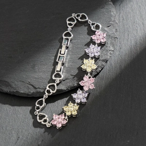 Silver bracelet with colorful AAA zircon flower charms on a textured black stone surface