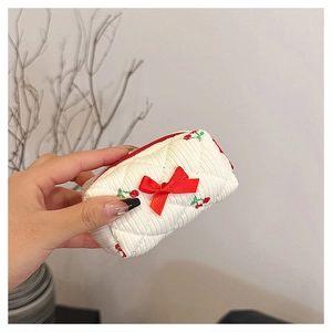 Close-up of a white quilted floral cotton makeup bag with red cherry embroidery