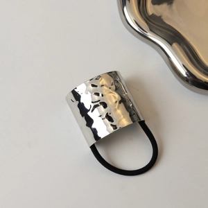 Detail of silver lava-textured metal buckle with black elastic hair tie for women