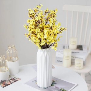 Yellow artificial flower bouquet in white geometric ceramic vase for home decor