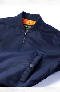Detail of navy bomber jacket featuring ribbed collar, metal zipper, and orange lining