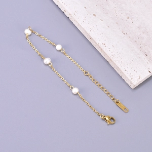 Detailed macro view of gold chain bracelet with freshwater pearls and K18 engraving tag
