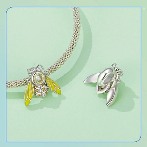 Macro detail of a bee pendant with yellow enamel and sparkling crystals on a silver mesh bracelet