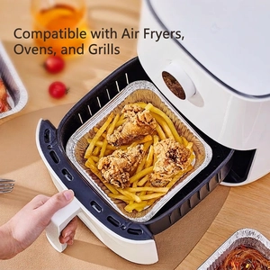 Square food-grade aluminum foil liners in air fryer with roasted chicken and fries