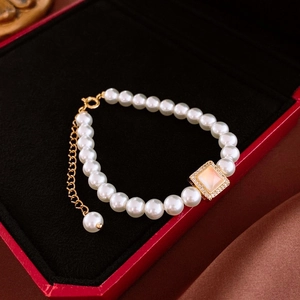 Gros plan du bracelet de perles avec pierre rose dans un écrin à bijoux rouge
