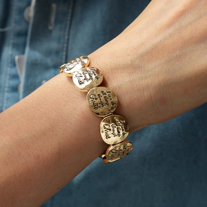 Détail de breloques en métal doré gravées de citations motivantes sur un bracelet chic