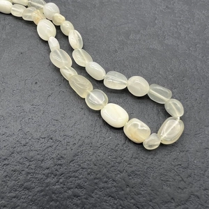 Macro shot of natural irregular tumbled stone beads on a textured grey background