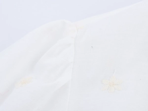 Gros plan détaillé du tissu en coton blanc avec broderie florale exquise sur l'épaule