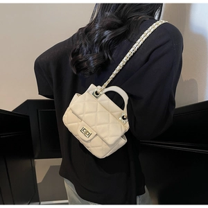 Beige quilted handbag with gold chain strap shown on model to display size and style