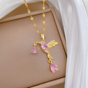 Macro detail of golden hummingbird necklace with pink pear-cut gems on white silk