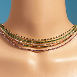 Close-up of stacked gold tennis necklaces featuring vibrant colorful zircon stones