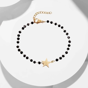 Detailed shot of black beaded bracelet with gold star pendant and adjustable chain clasp