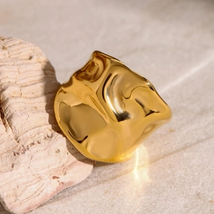 Close-up of gold 18k stainless steel ring with hammered texture on natural stone