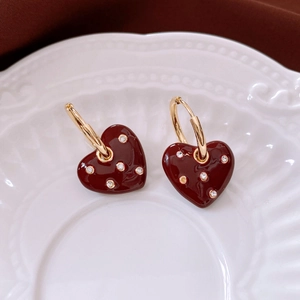 Detailed view of wine red heart earrings with crystals on a white embossed plate