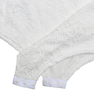 Detailed close-up of white lace bodysuit featuring high-quality floral fabric and snap closure