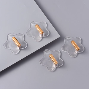 Detail eines sternförmigen transparenten Klebehakens mit luxuriösem goldenem Metallhaken