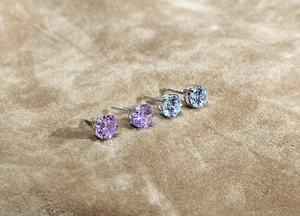 Macro detail of classic four-prong silver studs with pink and clear zircon stones