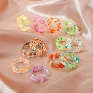 Flat lay of colorful acrylic resin fruit rings on pink silk background for summer fashion
