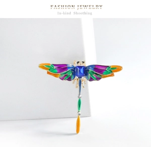 Macro shot of colorful enamel dragonfly brooch with blue gemstone and fine crystals